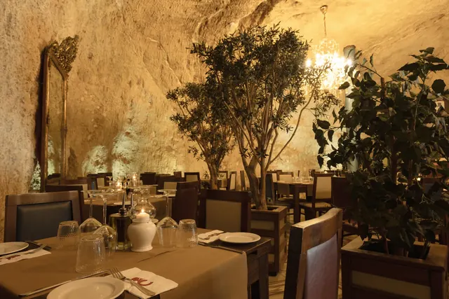 Candlelit dining room with stone walls and olive trees